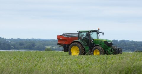 Tractor John Deere echando fertilizante con abonadora. Tipo de sembradora a voleo. Política agraria-PAC