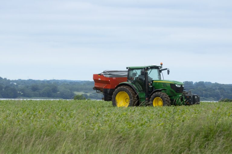 Tractor John Deere echando fertilizante con abonadora. Tipo de sembradora a voleo. Política agraria-PAC